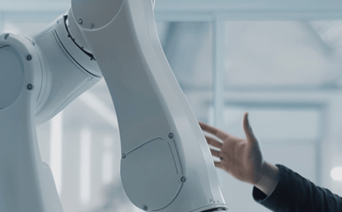 Close-up of a white industrial robotic arm with a human hand reaching toward it.